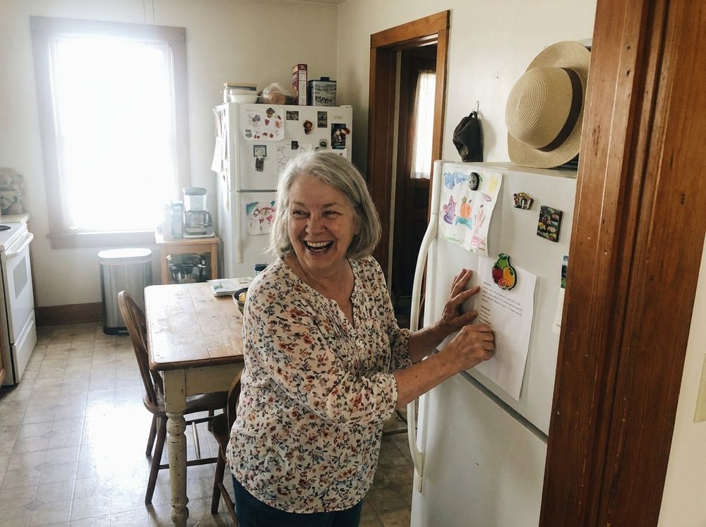 Rosa putting the weekly sheet up on the refrigerator